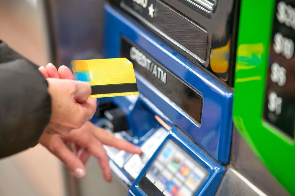 A person inserting a credit card into an ATM machine, representing secure transactions, banking services, and cash withdrawal