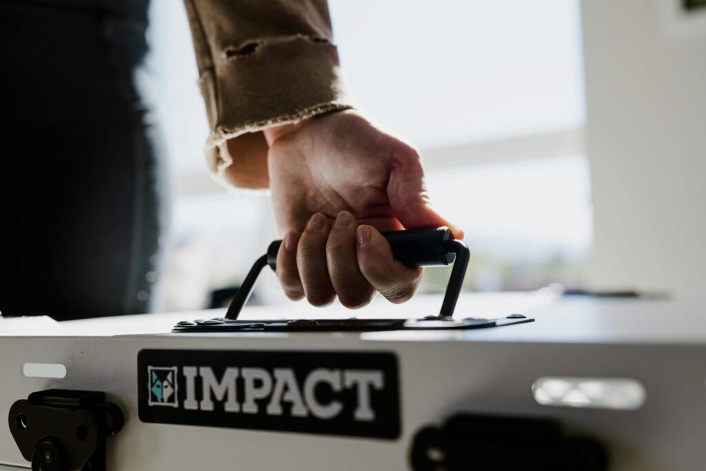 A person holding the handle of an Impact-branded equipment case, representing Extended Warranties