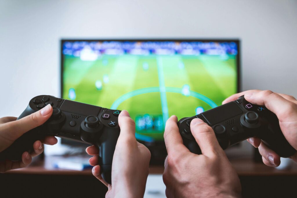 Two people holding game controllers while playing a soccer video game on a television screen