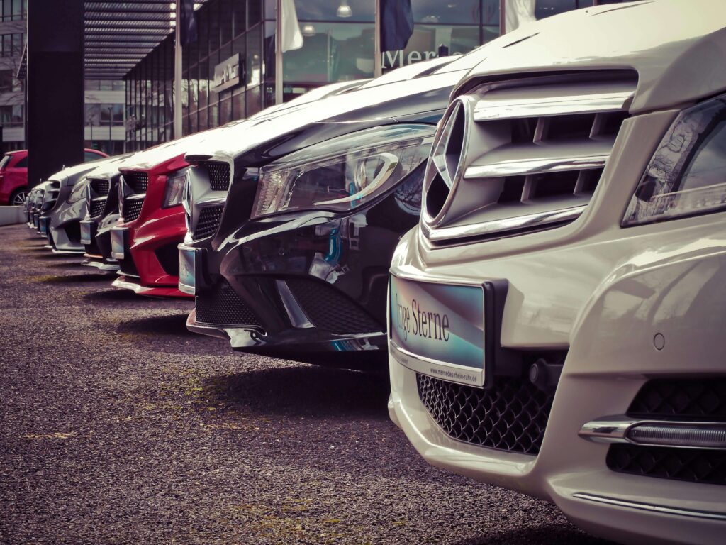 A row of luxury cars, including Mercedes-Benz, parked outside a dealership, symbolizing high-end vehicles, luxury car investment