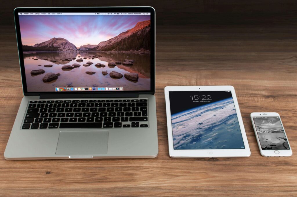 A laptop, tablet, and smartphone placed on a wooden desk, representing modern technology, digital devices, and online connectivity