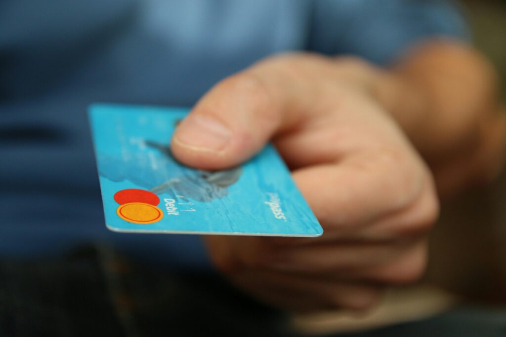 A person handing over a blue debit card, representing secure digital transactions, debit card payments, and electronic banking